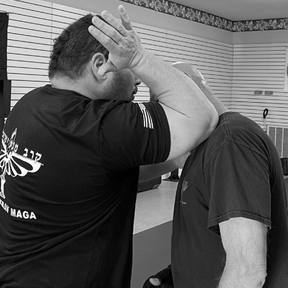 Coach Chris Crossman teaching Krav maga, and demonstrating striking the colar bone in self defense with an elbow strike.